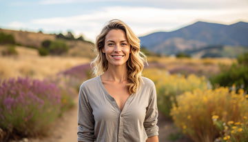 Woman standing in a field with lavender and yellow flowers, mountains in the background